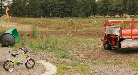 En barncykel bredvid en lantbruksmaskin, foto.