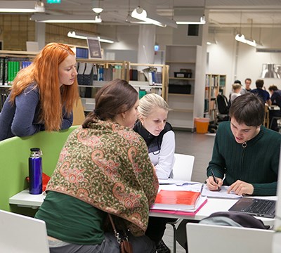 Fyra personer studerar tillsammans i SLU:s bibliotek i Umeå. Foto.