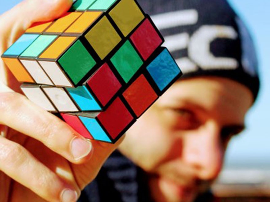A man holds upp a rubics cube, photo.