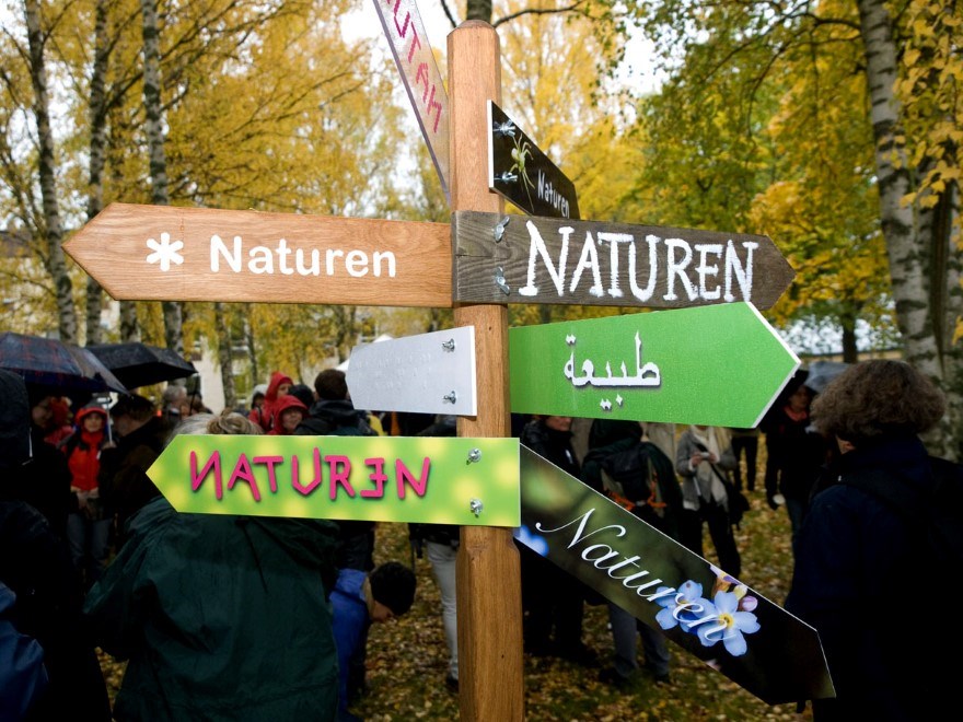 En stolpe med flera skyltar med texten ”Naturen” som pekar åt olika håll. Foto.