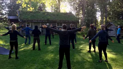 En grupp står utomhus i en ring och gör qigong.