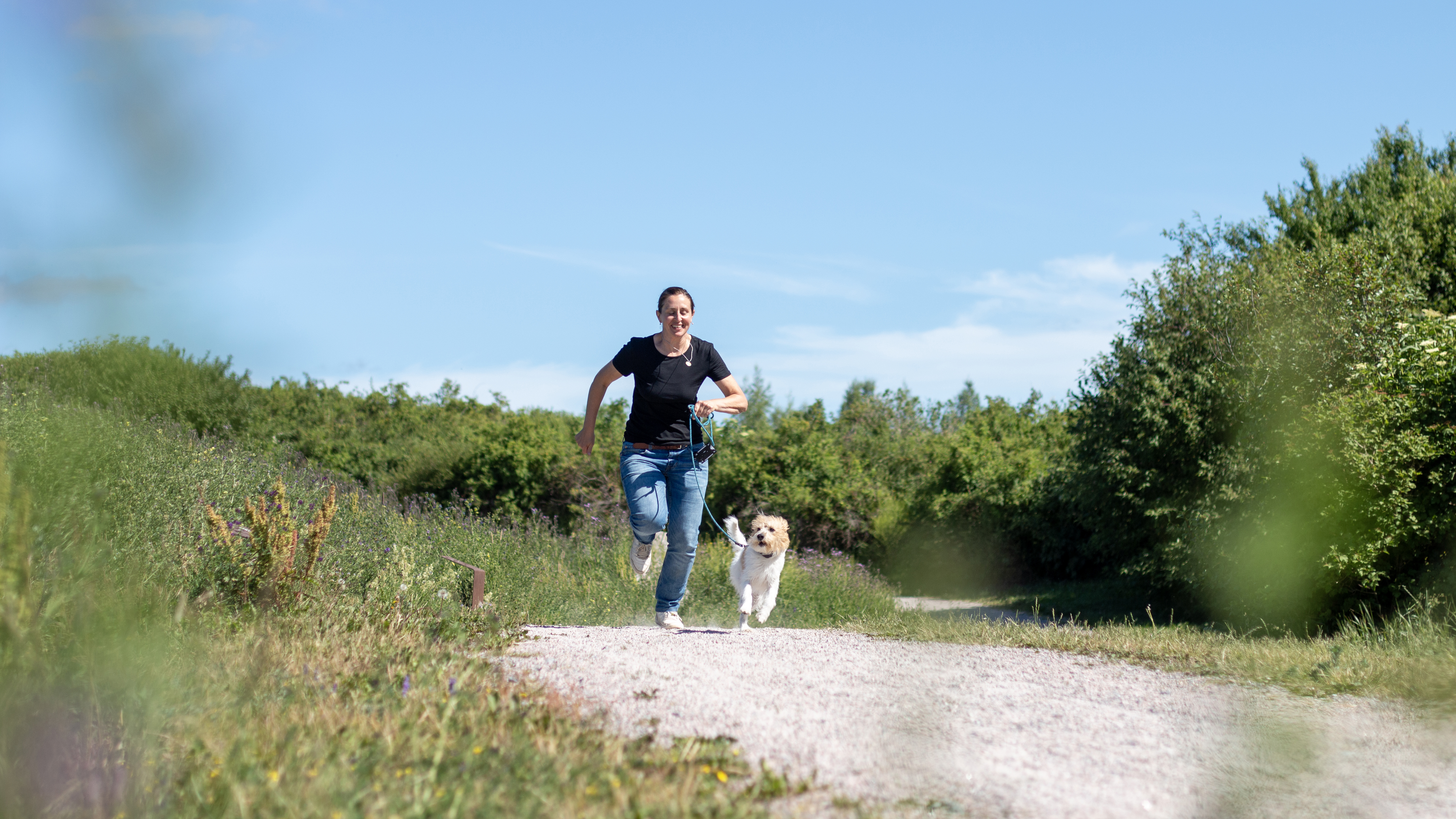 A woman and a dog running together. Photo.
