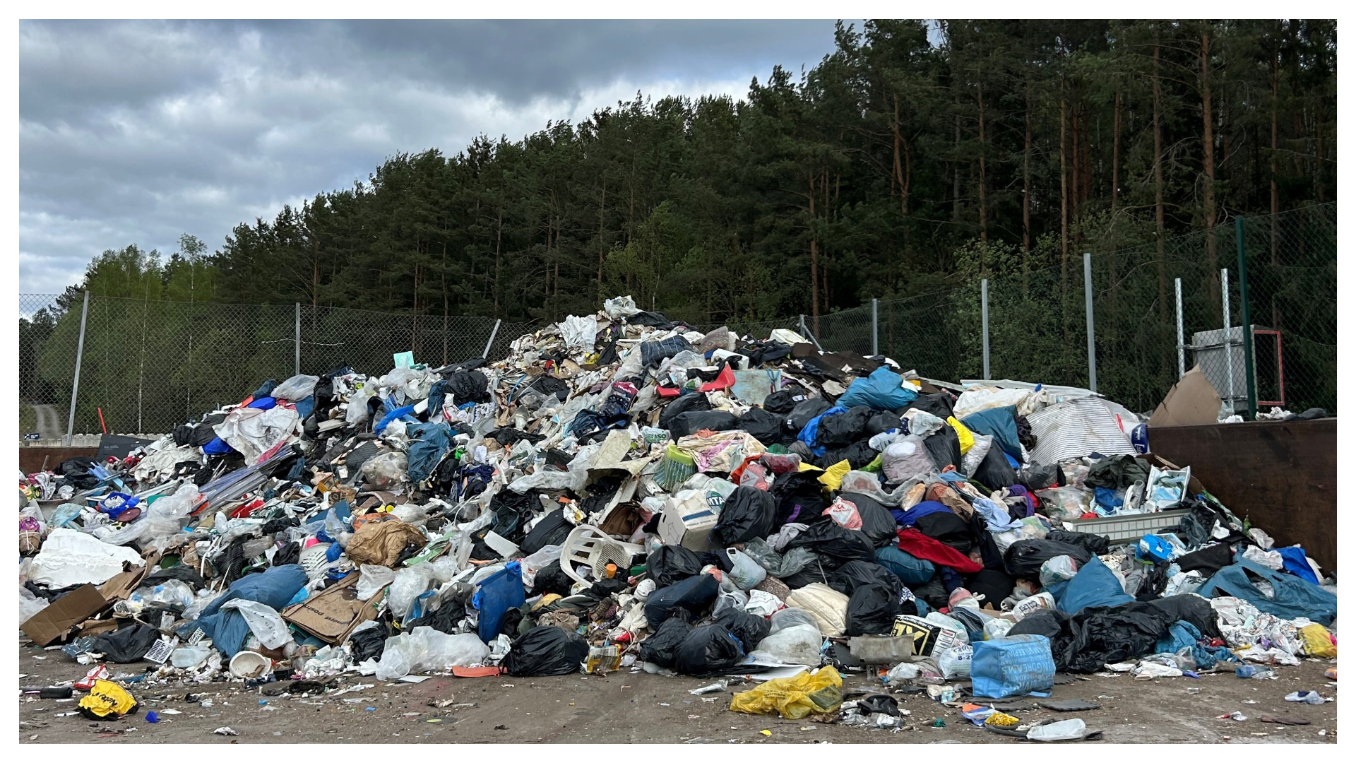 Foto av en avfallsanläggning med stor hög av sopor utomhus.