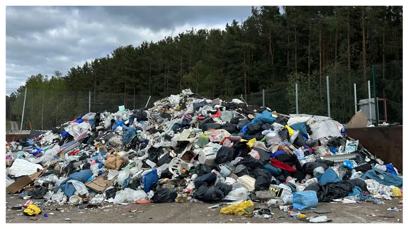 Foto av en avfallsanläggning med stor hög av sopor utomhus.