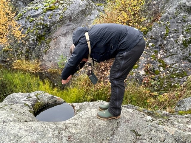 En person står på ett berg. Framför sig har hon en jättegryta som formats av en sten under senaste istiden. 