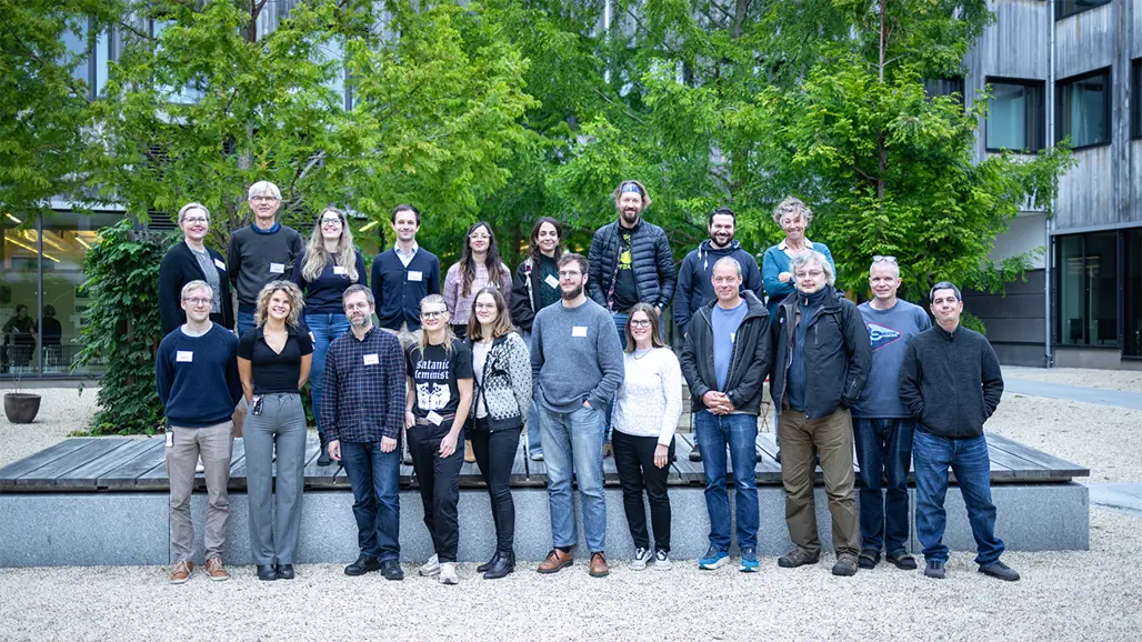 Grupp av leende människor står uppställda på innergård. Foto