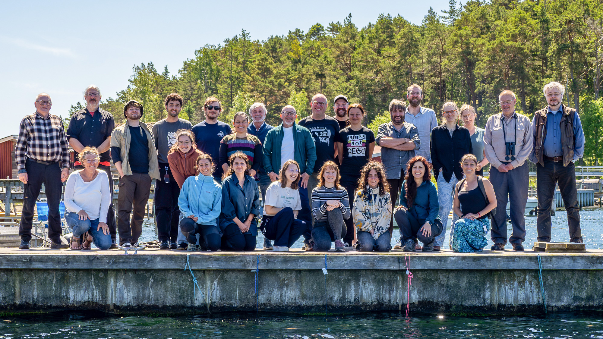 Gruppbild på brygga i solig skärgårdsmiljö. Foto