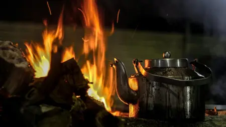 En tekanna står nära en eld.