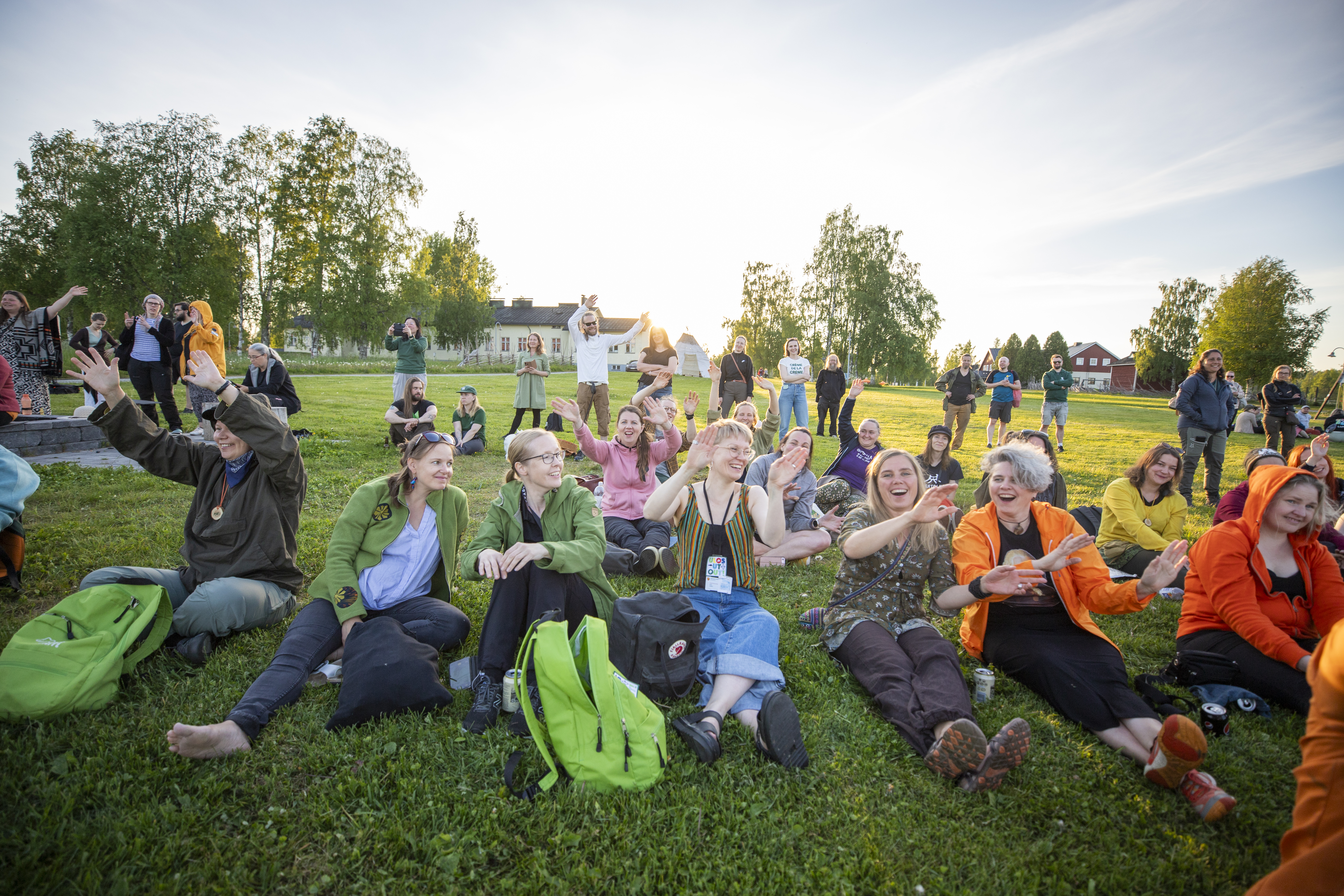 Många personer sitter på en gräsmatta och är glada