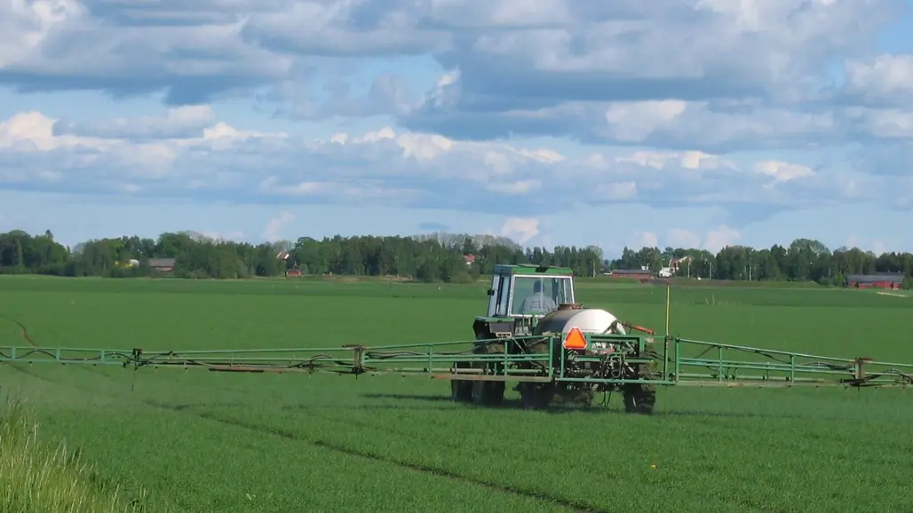 Traktor som sprutar bekämpningsmedel på ett fält