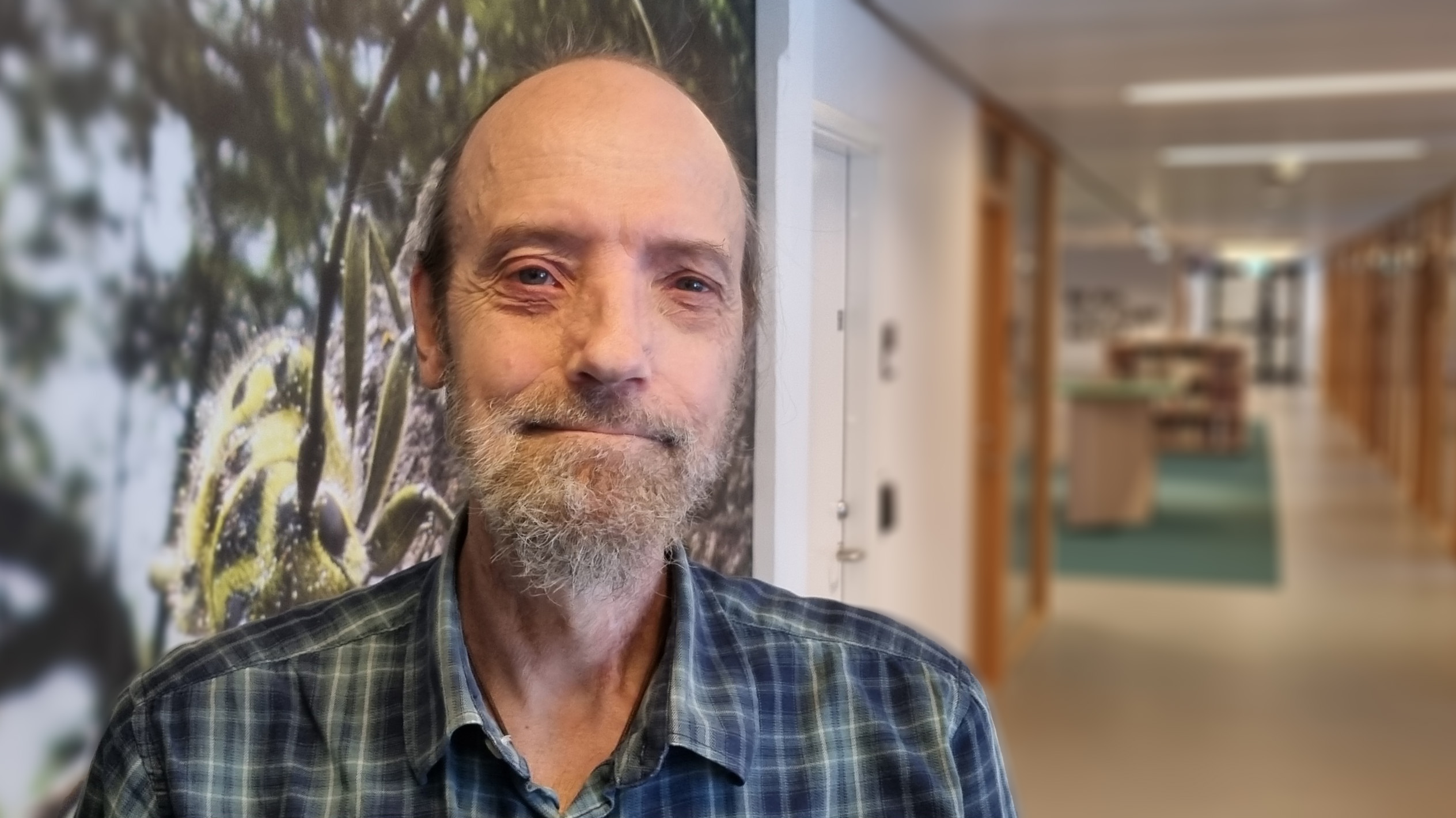 Man med kalt huvud, hästsvans och grått skägg står i korridor. Foto