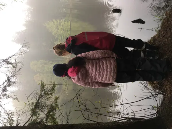 Två barn står och ser ut över en dimmig sjö