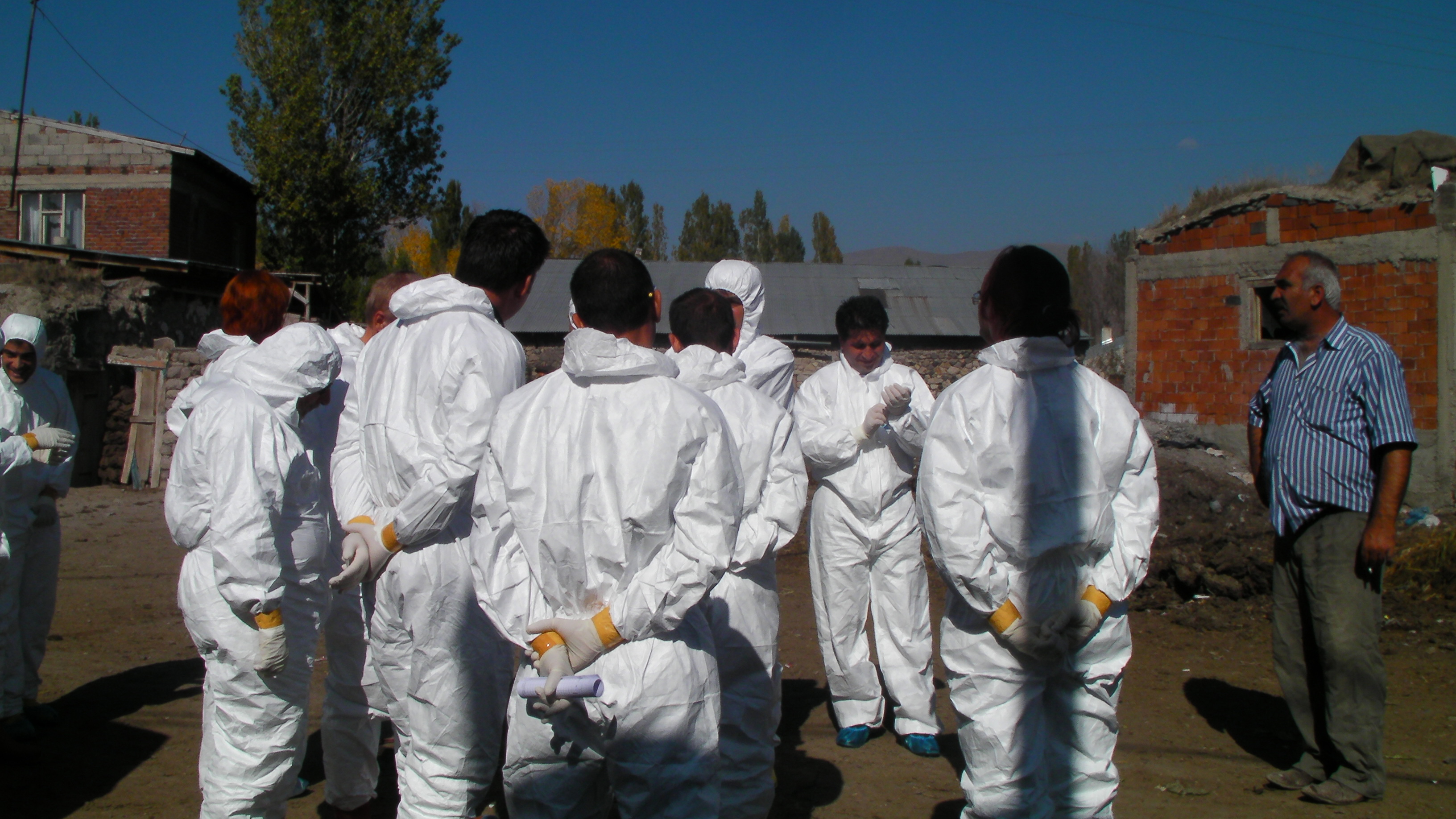 Foto av en grupp människor iklädda vita skyddskläder stående utomhus.