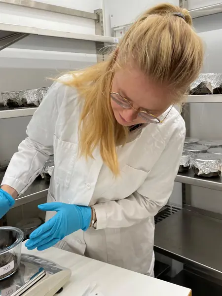 A blonde woman in a lab coat is performing a laboratory experiment. Photo.