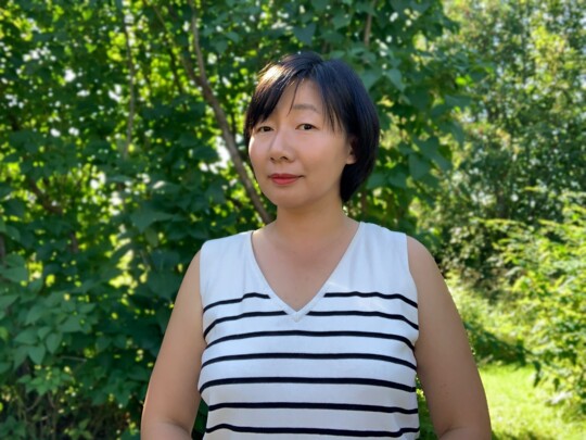 A woman standing in front of trees.