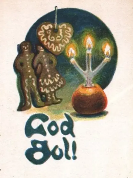 Två pepparkaksfigurer tittar på ett tänt stearinljus som står nerstucket i ett rött äpple. Ovanför pepparkaksfigurerna hänger ett pepparkakshjärta.