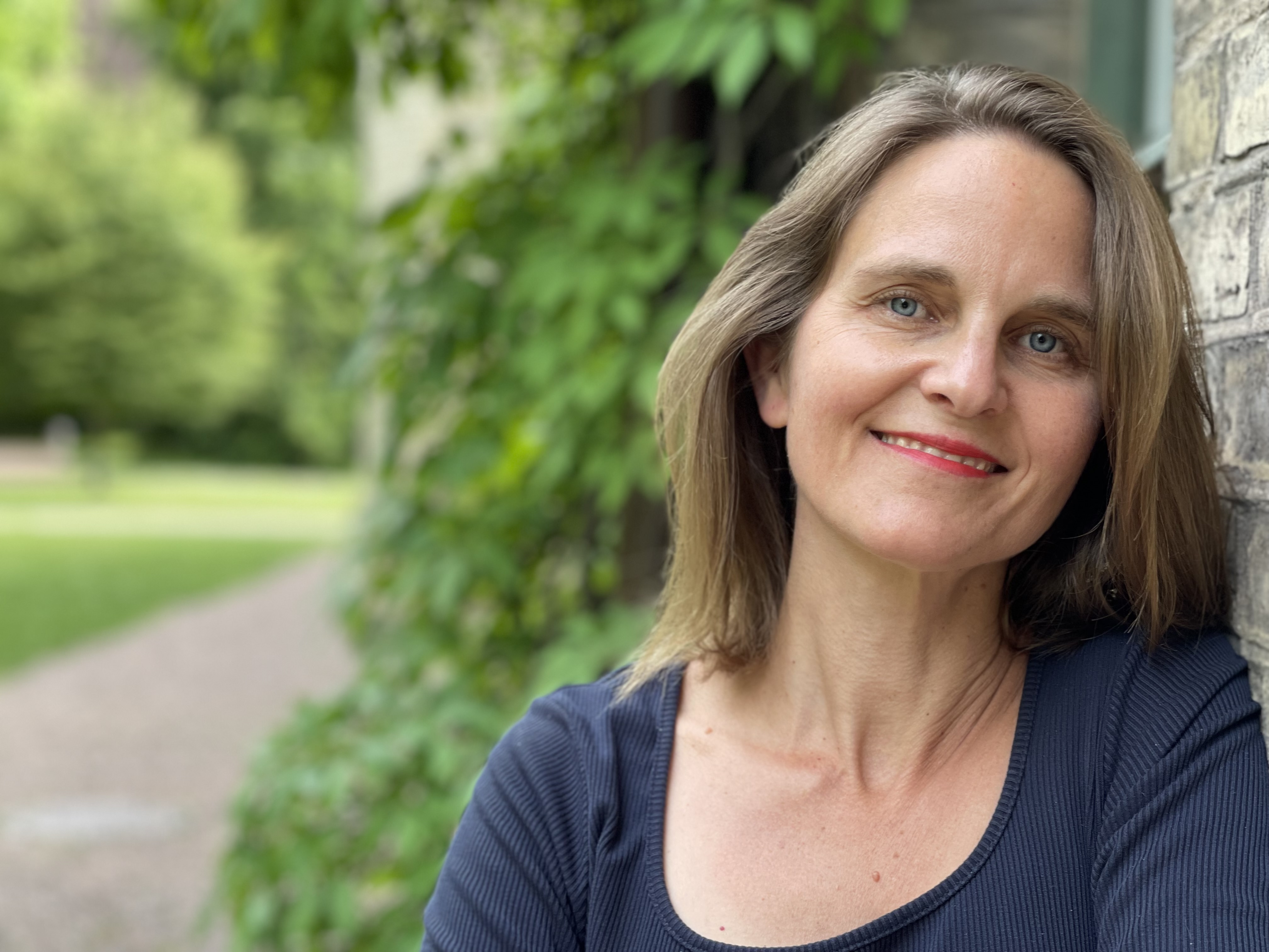 Foto på kvinna i grönskande bakgrund. 