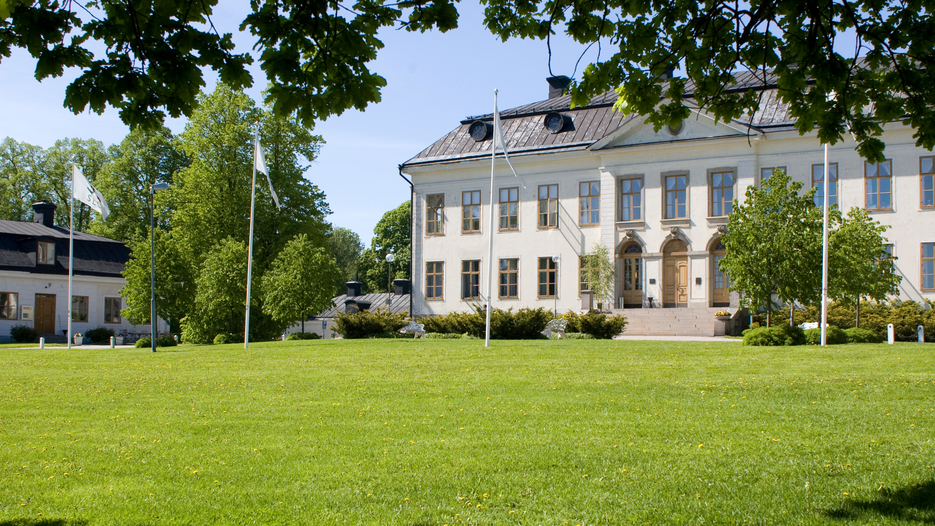 Den vita herrgården och SLU:s flaggor i Skinnskatteberg. 