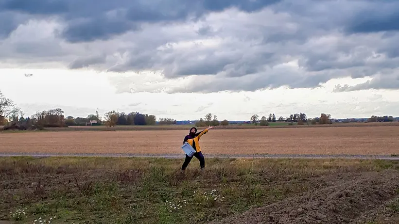 A person standing on an agricultural field. Photo.