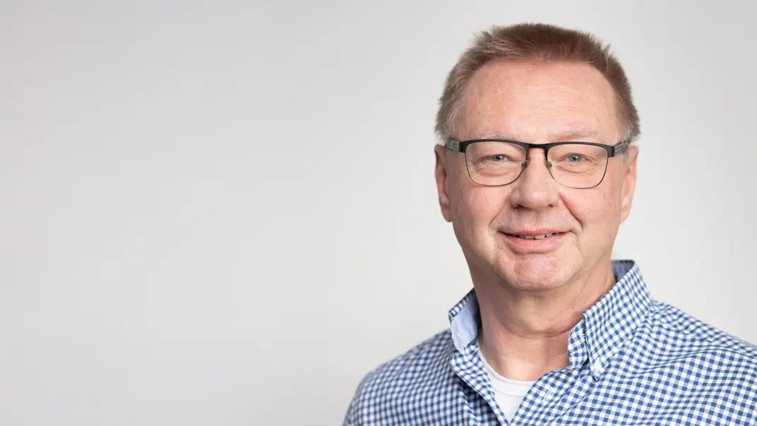 Portrait photo of a man against a gray background.