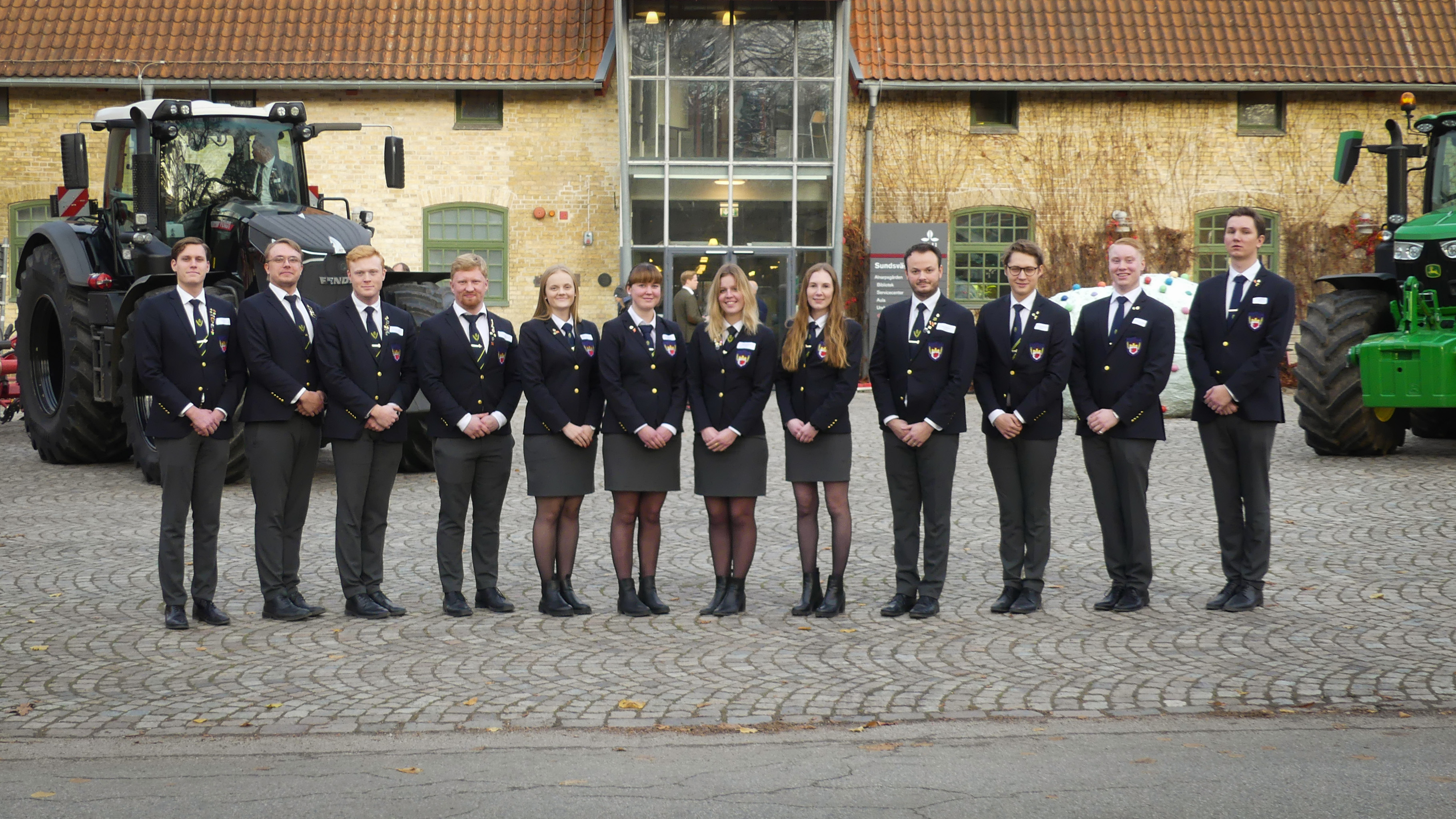 Lantmästarkåren står mellan två traktorer framför Alnarpsgården