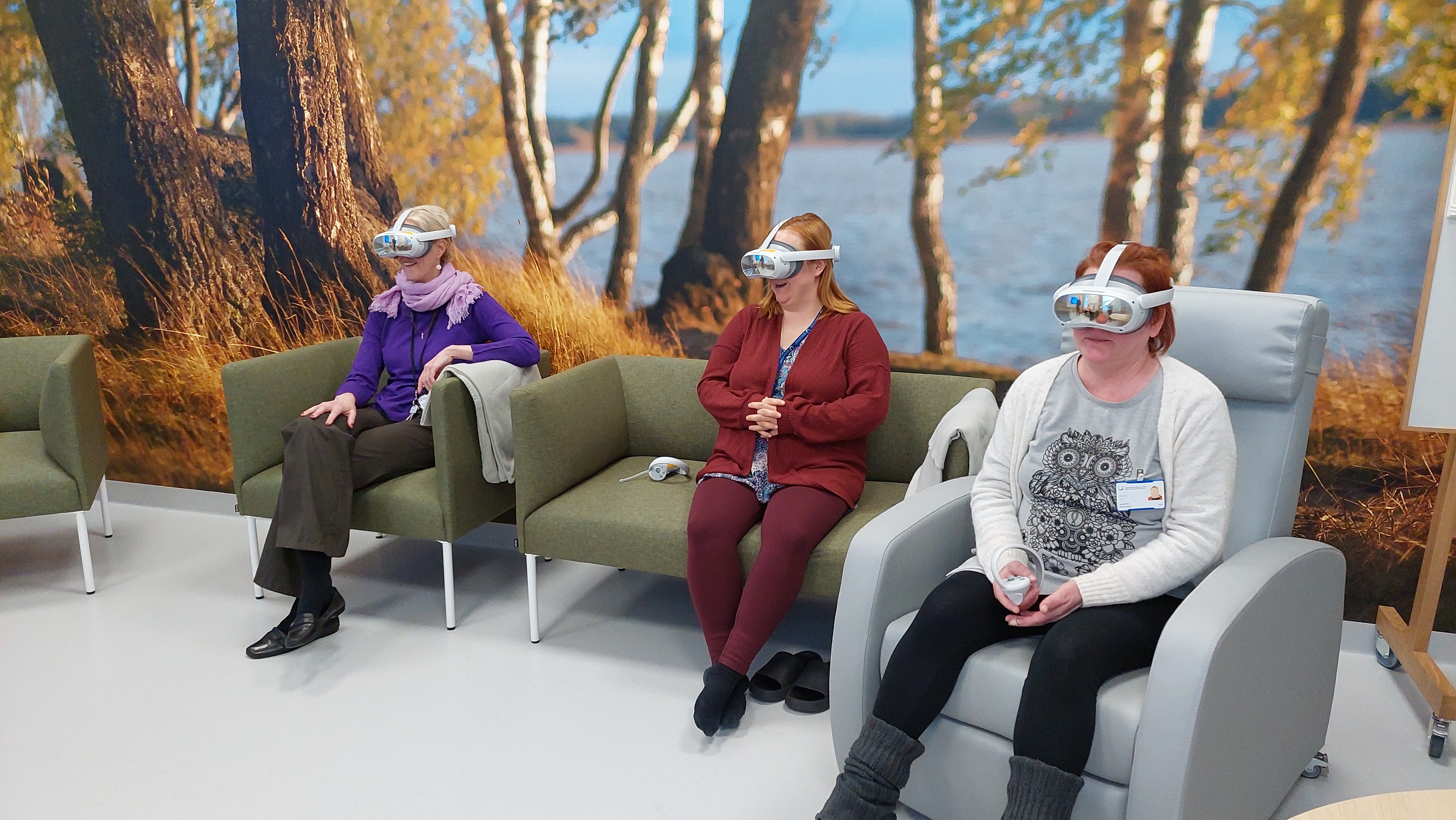 Three persons with VR-glasses in front of nature picture wall