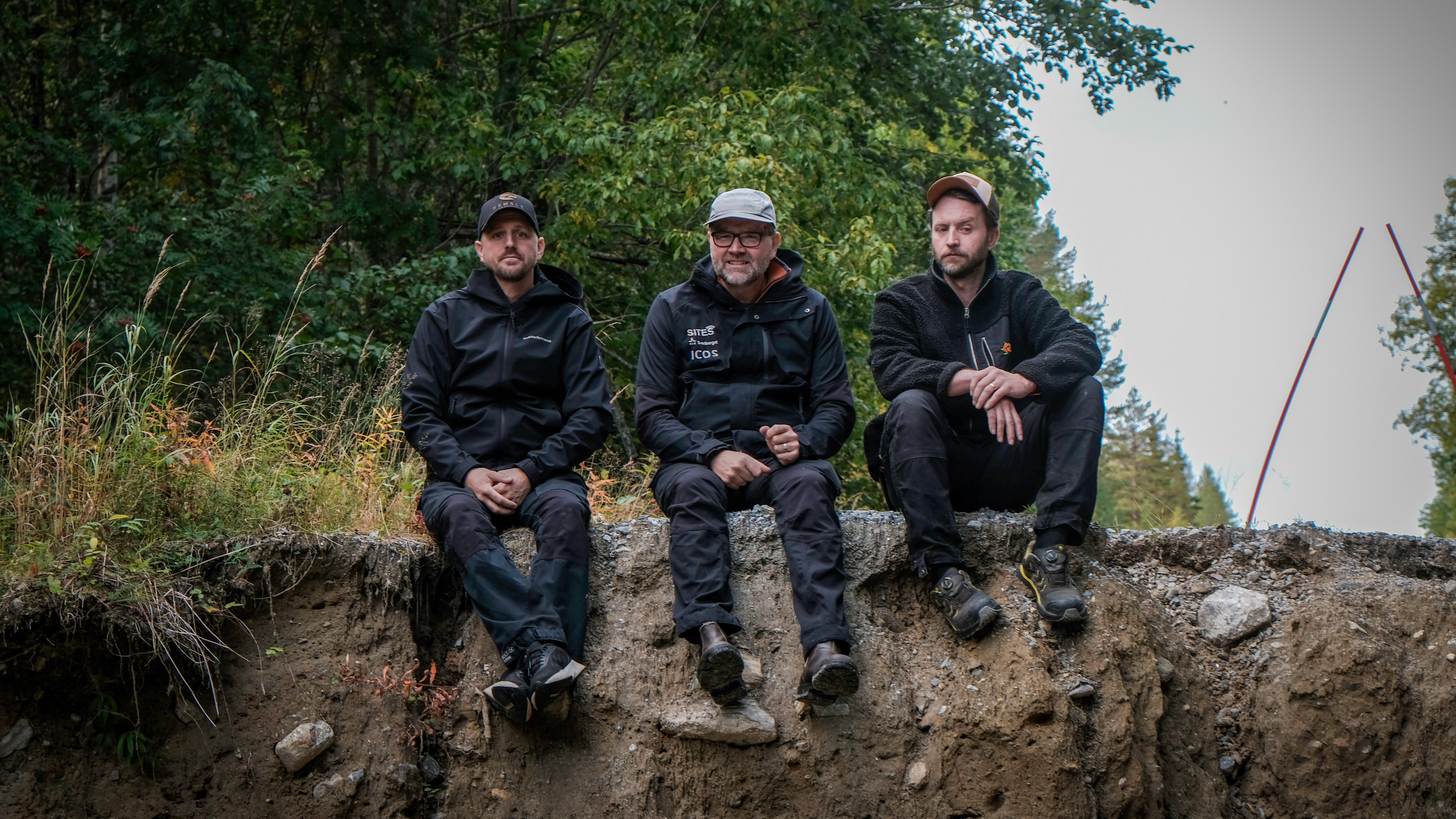 Per Åström, Erik Sundin och Hjalmar Laudon sitter på kanten till ravinen som blev kvar när vägen sveptes med i vattenmassorna. Bild: Daniel Stjärna, SLU.