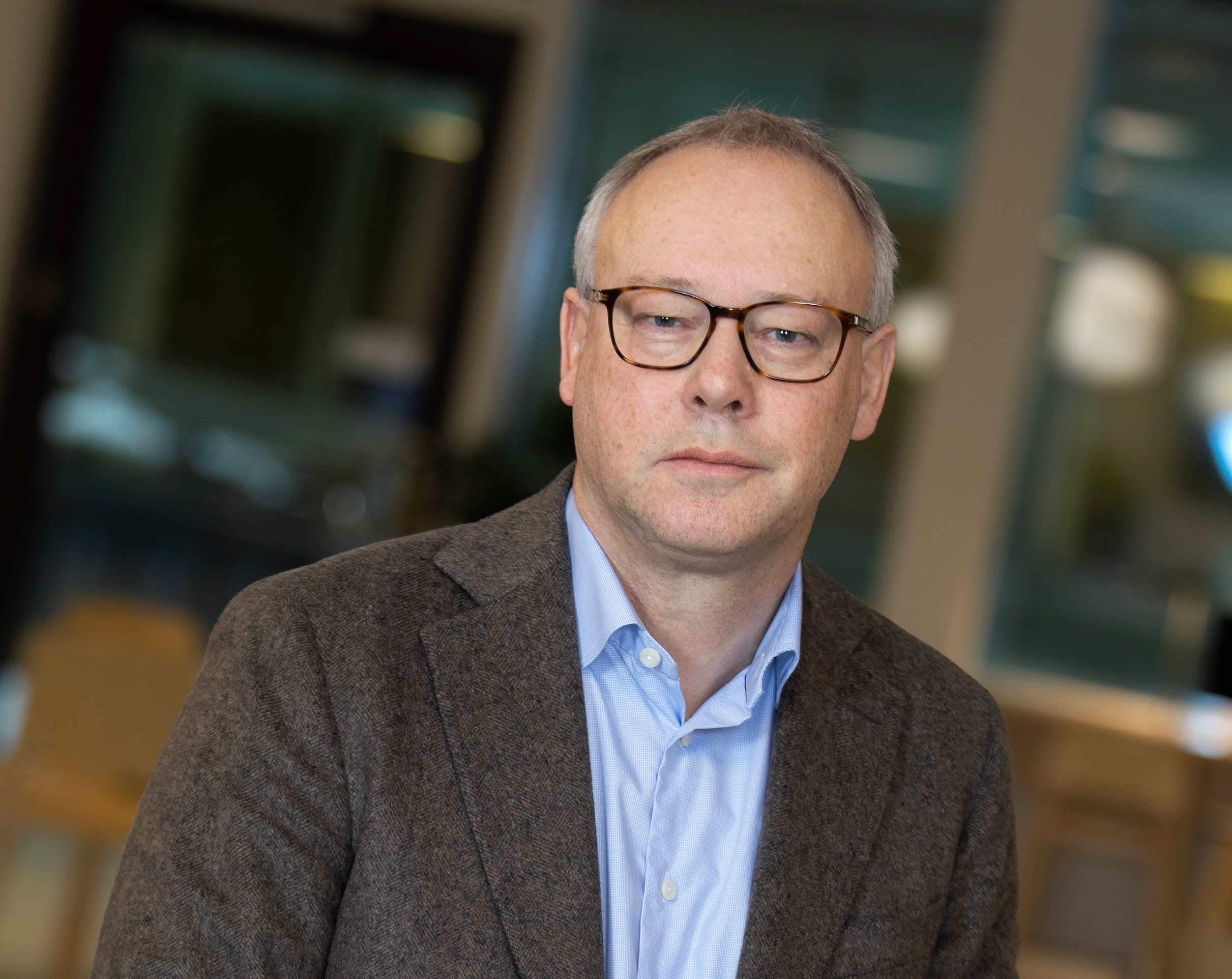 Man med glasögon och brun kavaj. Foto