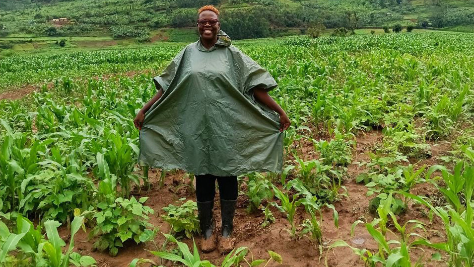 Kvinna i regnponcho på ett fält.