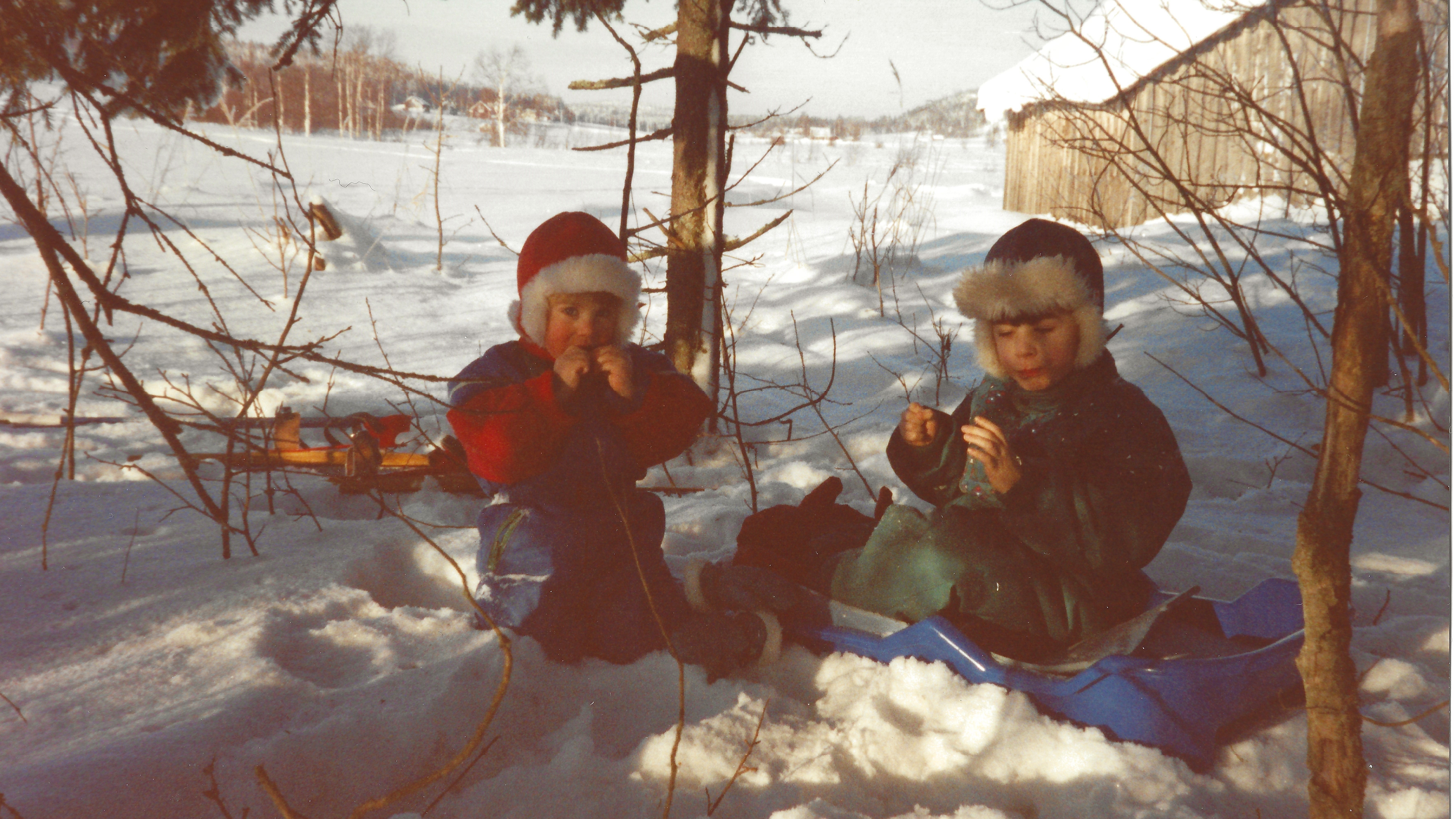 Två barn sitter i snön och leker