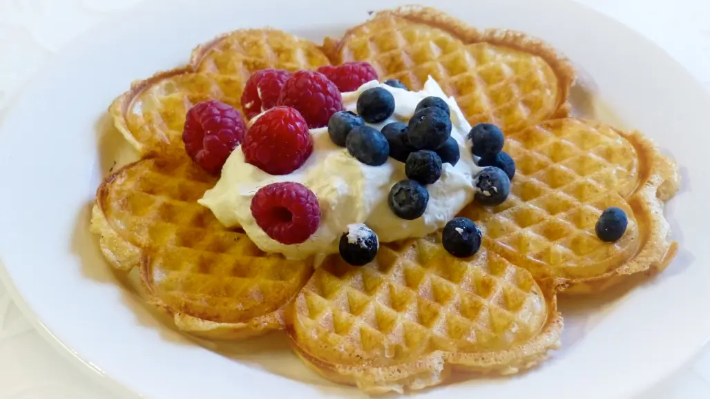 En våffla med grädde och bär. Foto.