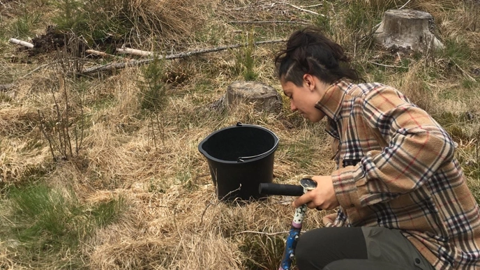 Person tar prov av jord vid plantskola. Foto.