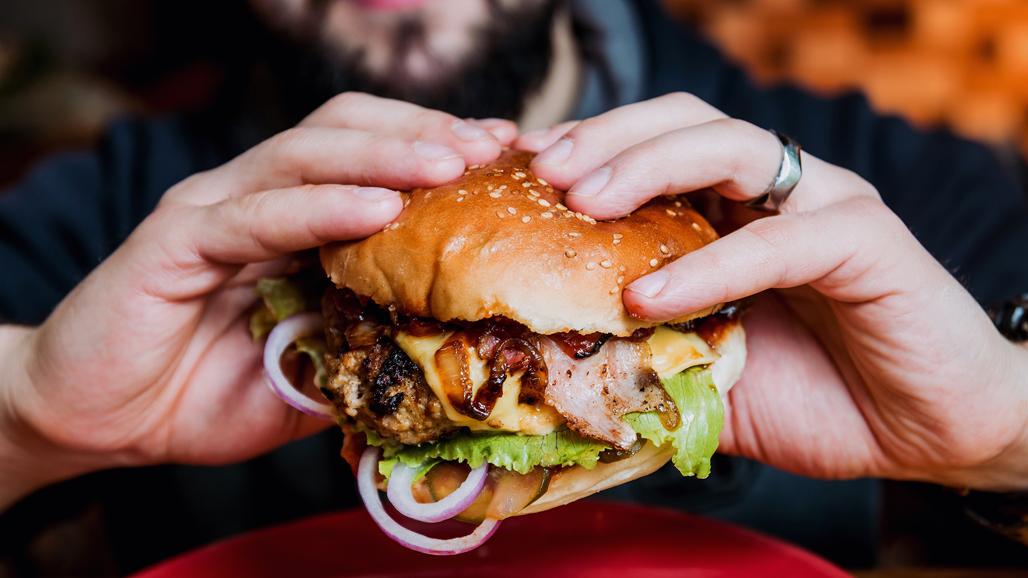 A person holds a burger in their hands.