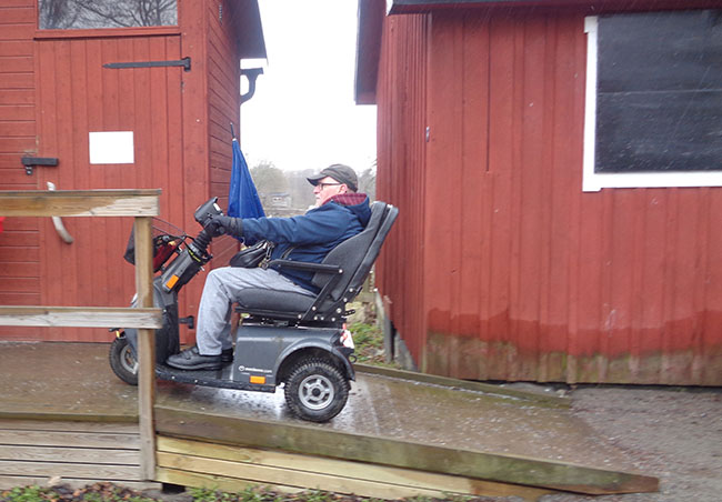 En person i en elrullstol åker uppför en ramp till ett tillgängligt dass vid Säby gård, Järfälla