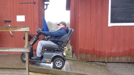 En person i en elrullstol åker uppför en ramp till ett tillgängligt dass vid Säby gård, Järfälla
