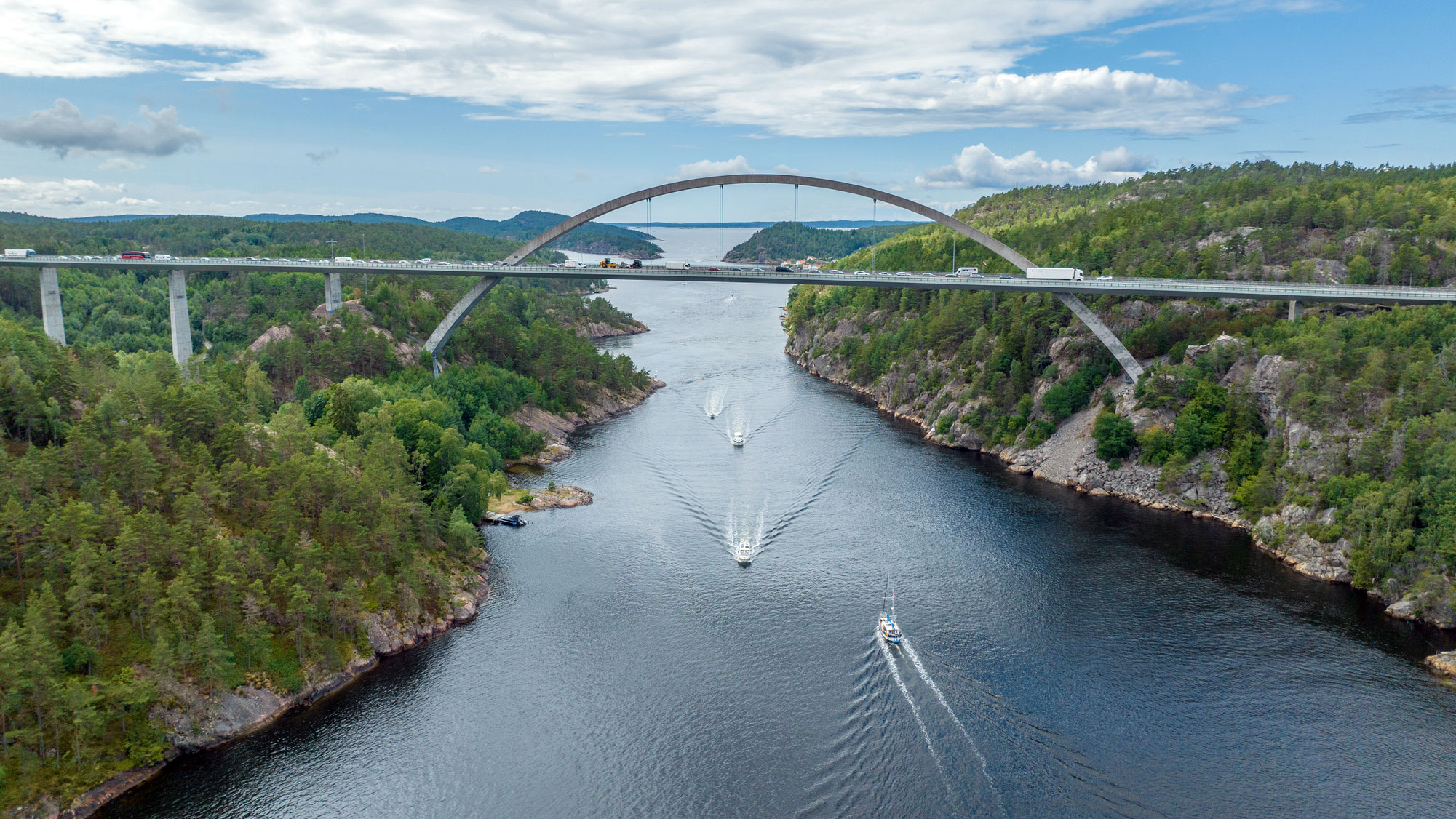 En hög bro över ett sund där båtar färdas. Foto.