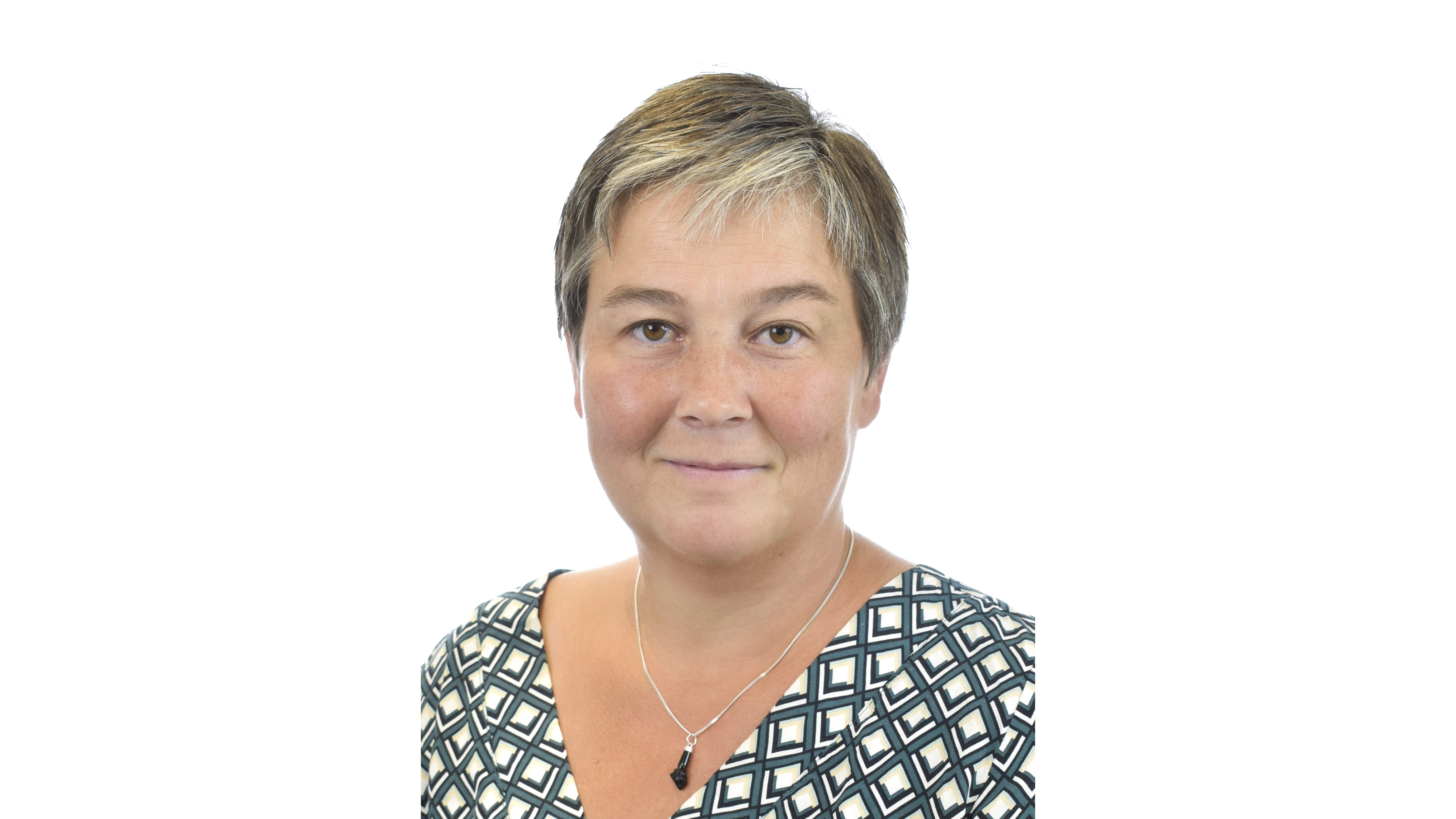 Leende, kortklippt och mörkblond kvinna med halsband och rutig blus. Foto