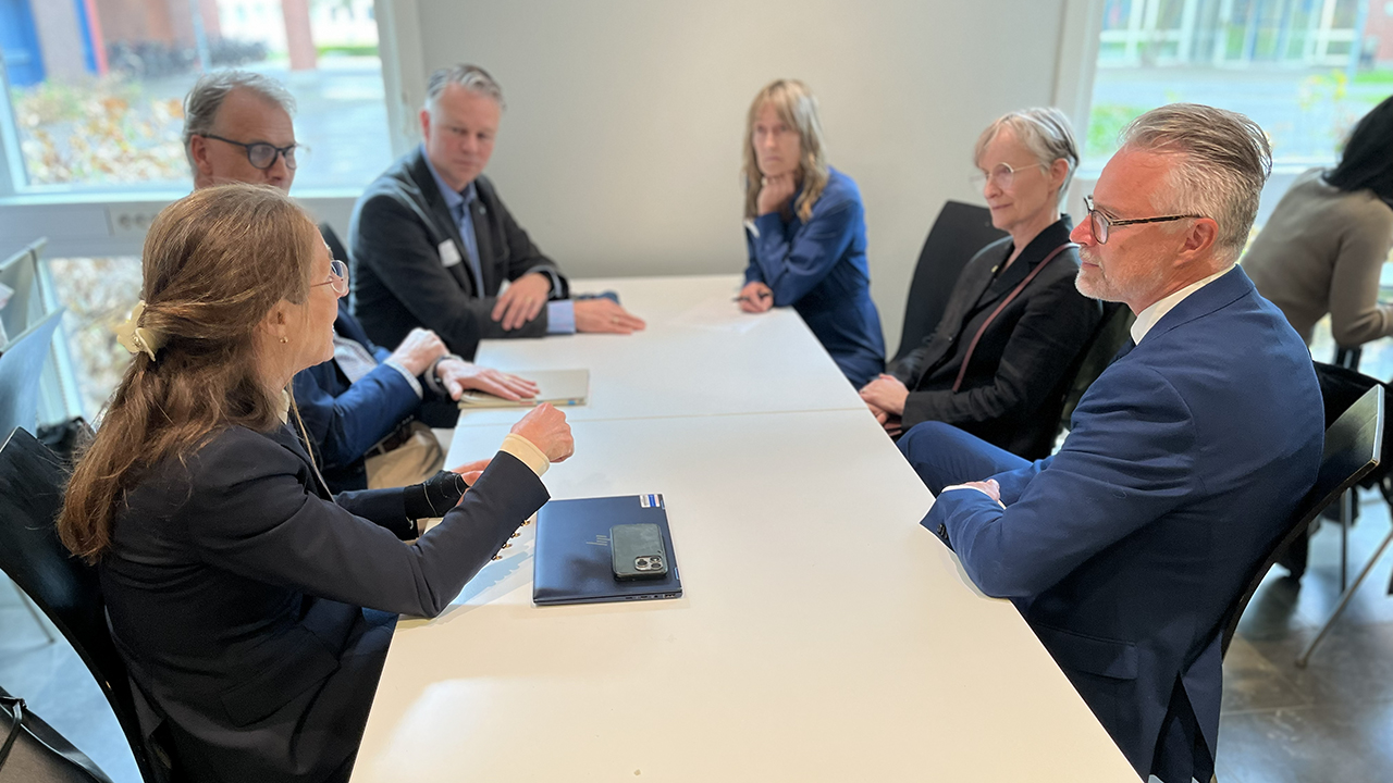 Sex personer runt ett bord diskuterar.
