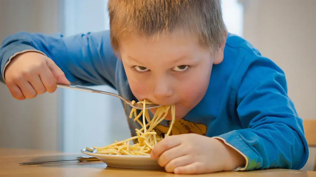 En pojke slevar i sig spaghetti från en tallrik. Foto: Andreas Breitling / Pixabay