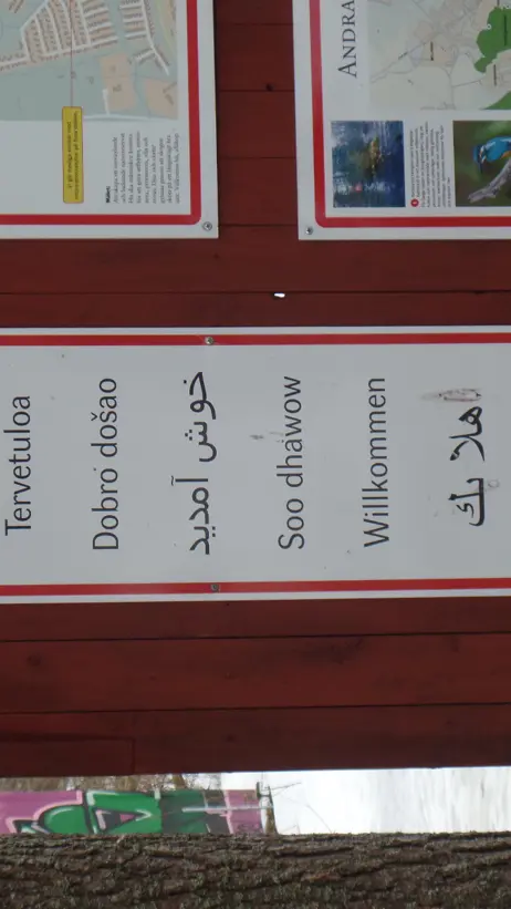 Foto: En flerspråkig välkomstskylt. Benedict Singleton, 2018.