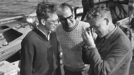 Tre män i en båt. Svartvitt foto.