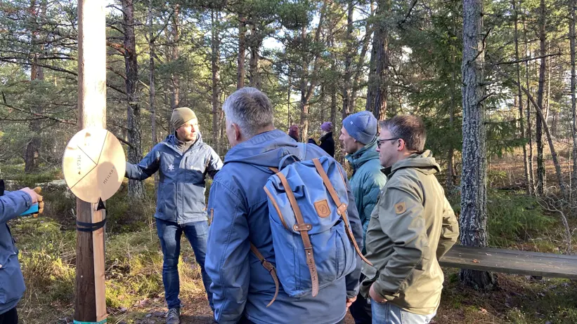 Personer står vid ett lyckohjul i skogen