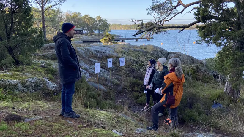 Fyra personer pratar på en höjd vid vatten