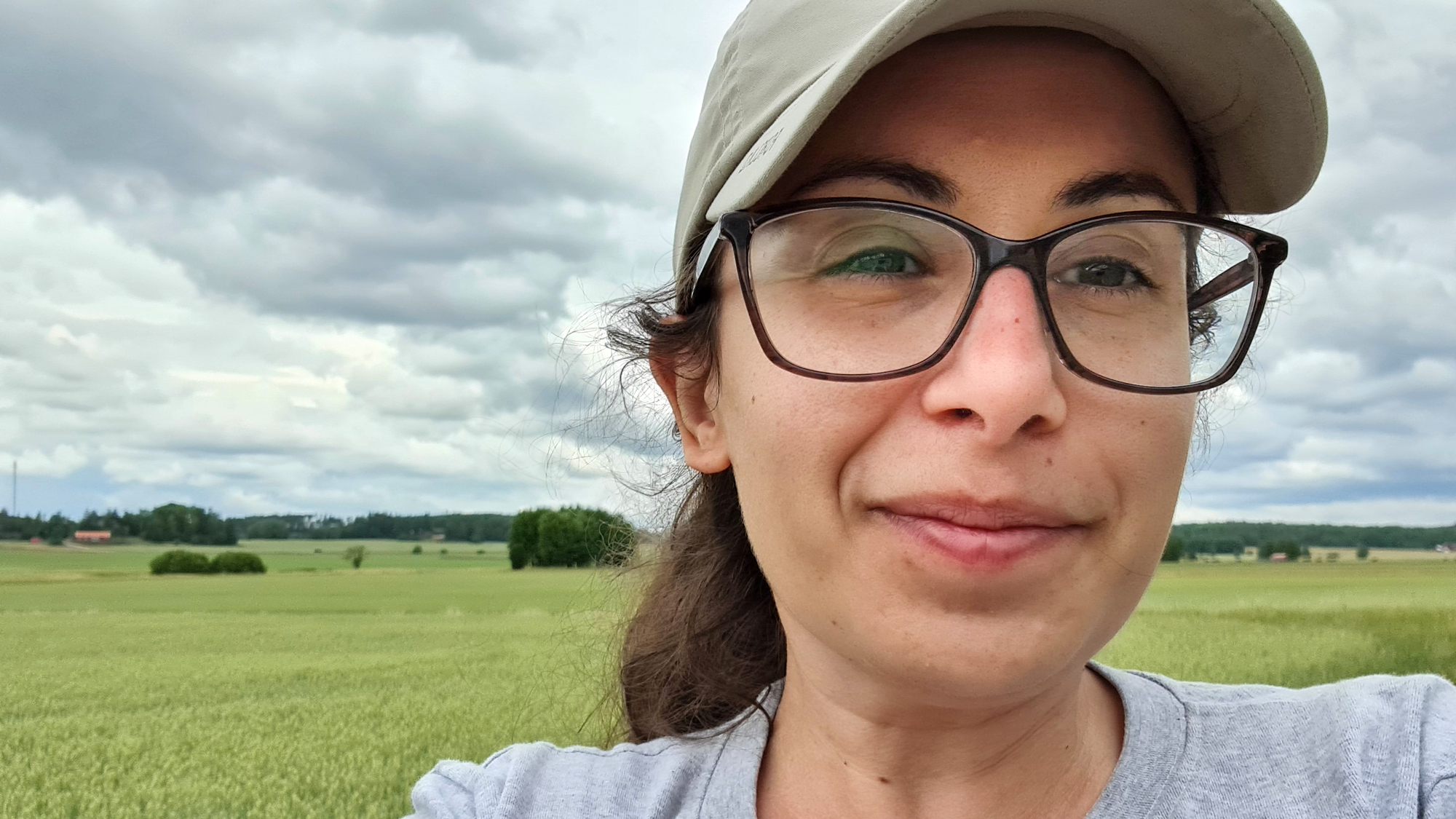A woman wearing a cap and glasses in a field. Photo.
