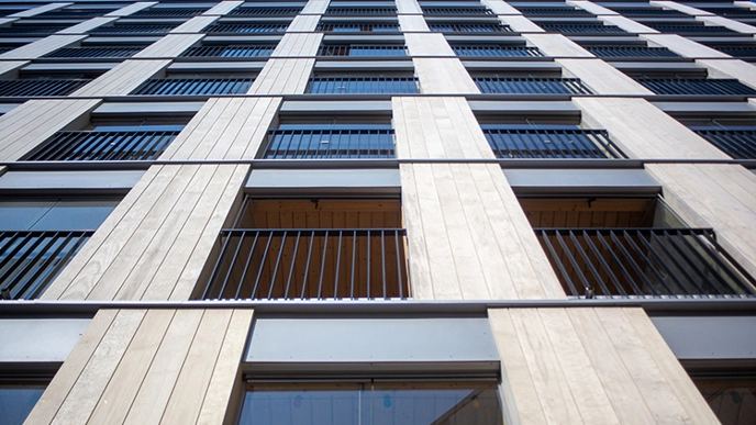 A wooden multistory building. The photo is taken close to the foot of the building looking up.