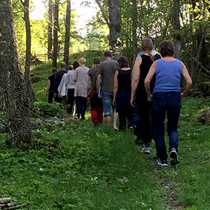 10 personer går på led på en stig i skogen. 