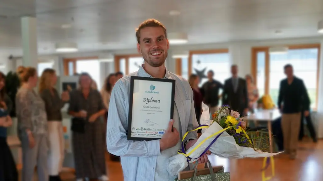 Harold Opdenbosch på disputationsdagen med inramat diplom, presenter och blommor.