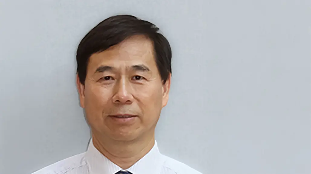 Portrait photo of a man against a grey background.