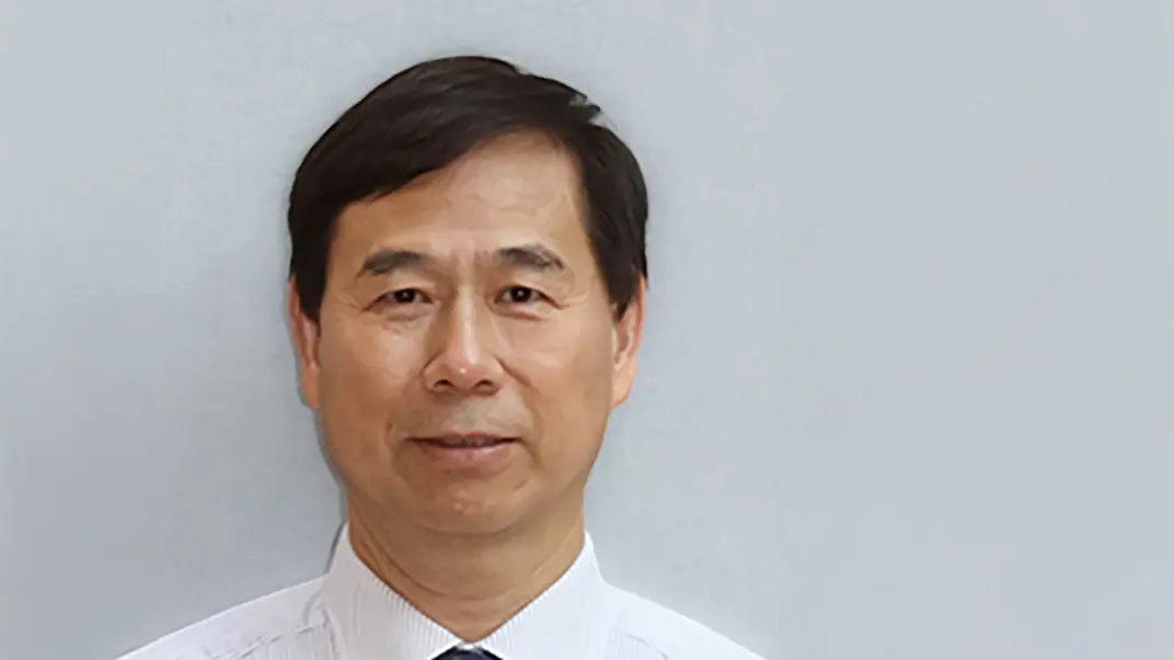 Portrait photo of a man against a grey background.