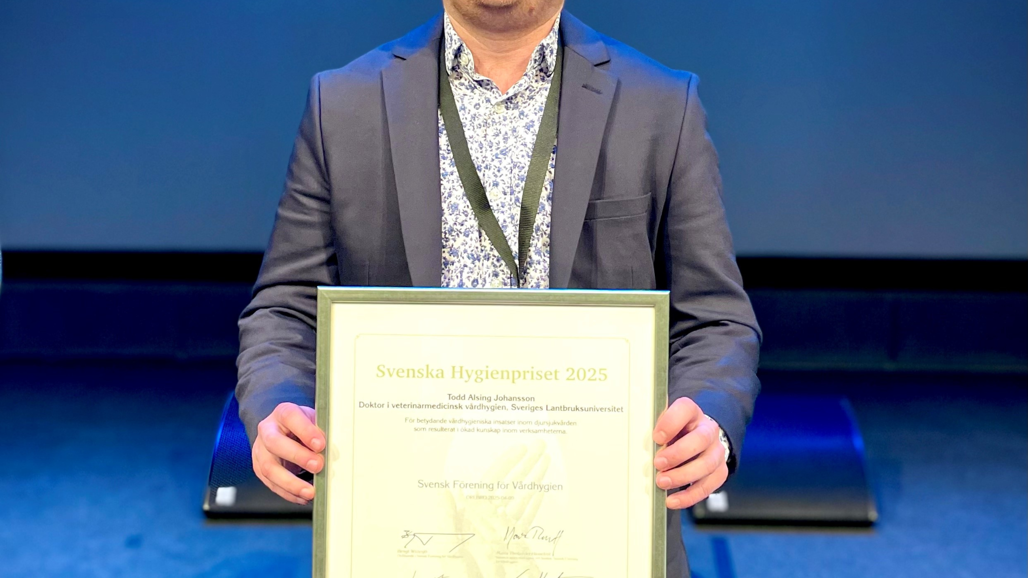 Man iklädd kostym som håller i ett diplom.